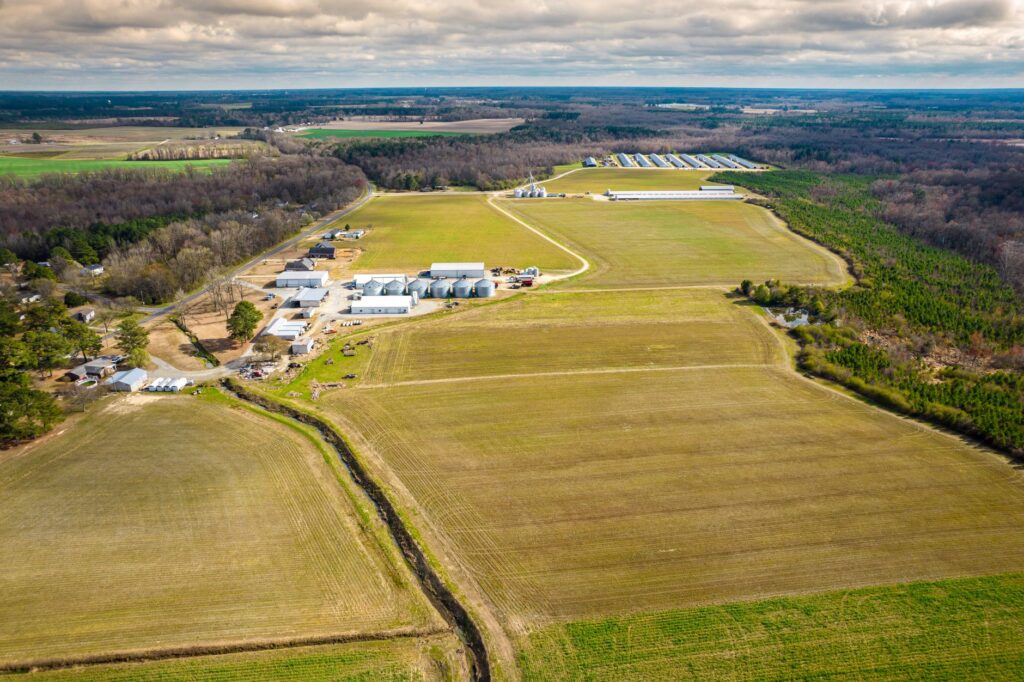 Aerial shot of extensive North Carolina farmlands, showcasing fields and structures.