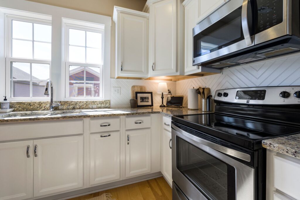 Bright and stylish modern kitchen featuring white cabinets and granite countertops with stainless steel appliances.