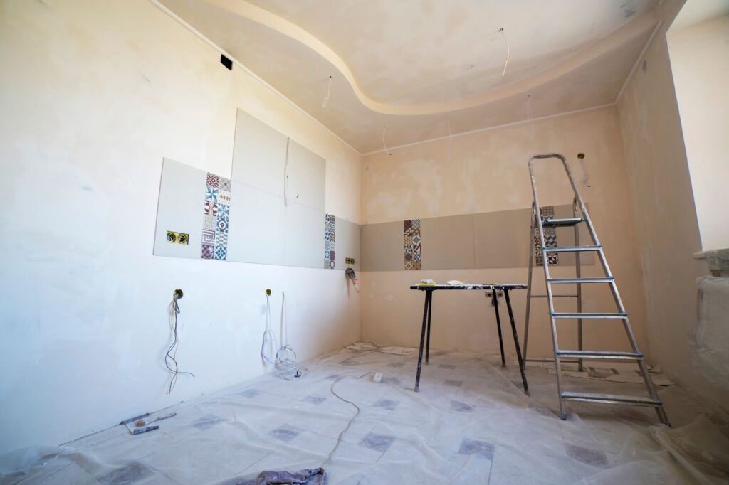 Interior view of a room under renovation with paint, tiles, and tools.