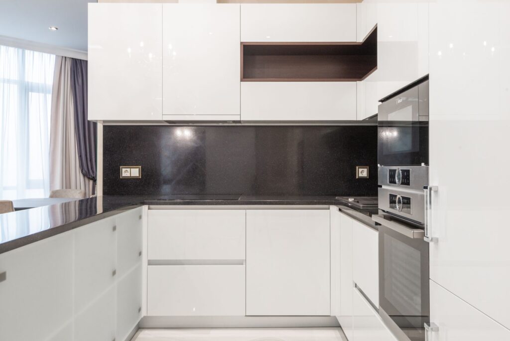 Sleek and clean modern kitchen with minimalist white cabinetry and black accents.
