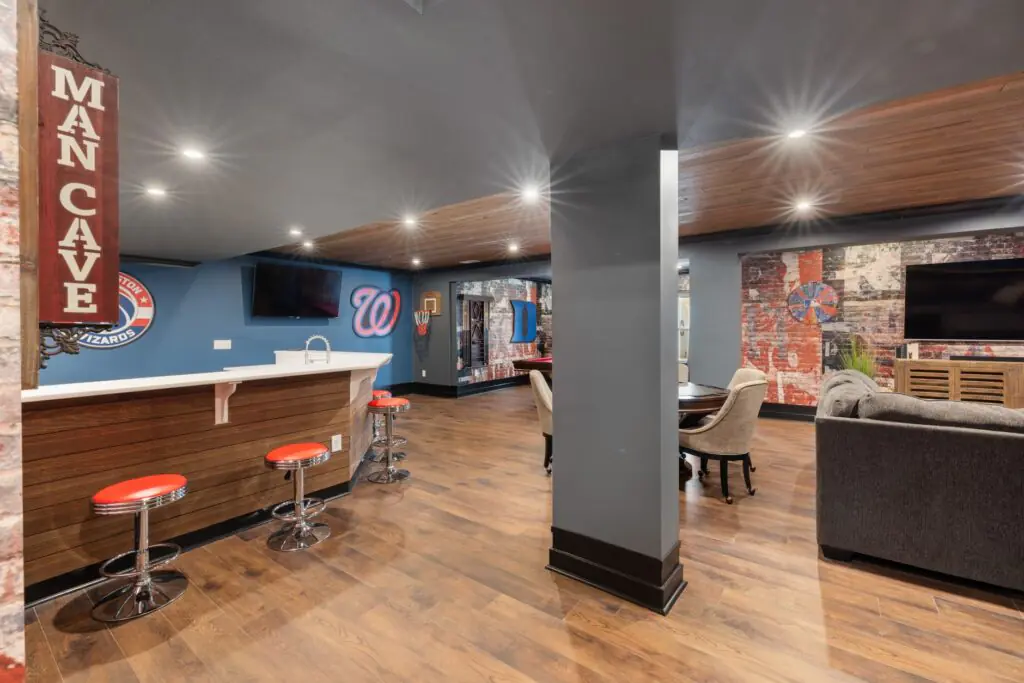 A modern man cave with a sleek bar setup, sports decor, and comfortable seating.