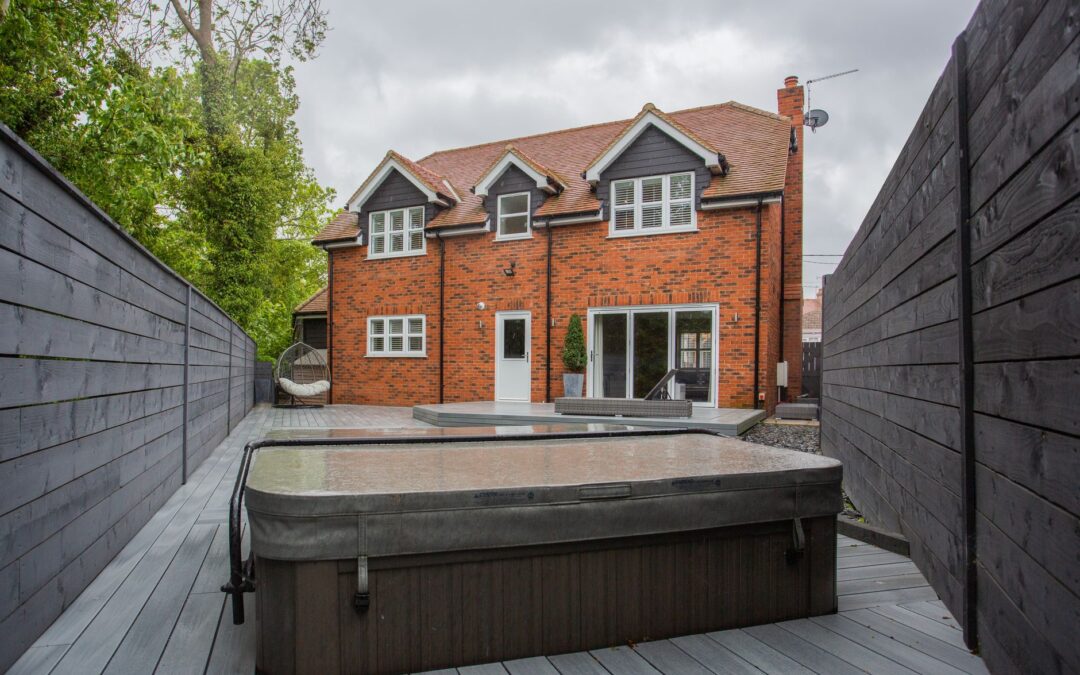A picturesque backyard view of a modern brick house with a jacuzzi.
