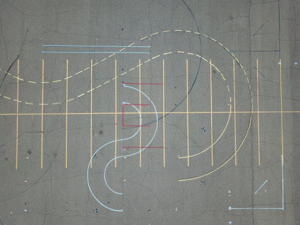A top-down shot of colorful abstract road markings on worn asphalt.