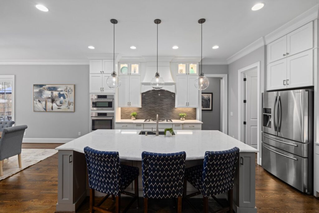 Bright modern kitchen featuring white cabinets, island, and stainless steel appliances.