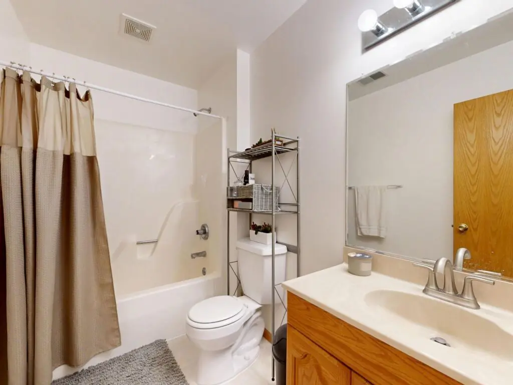 Contemporary bathroom featuring a beige shower curtain, sink, and toilet.