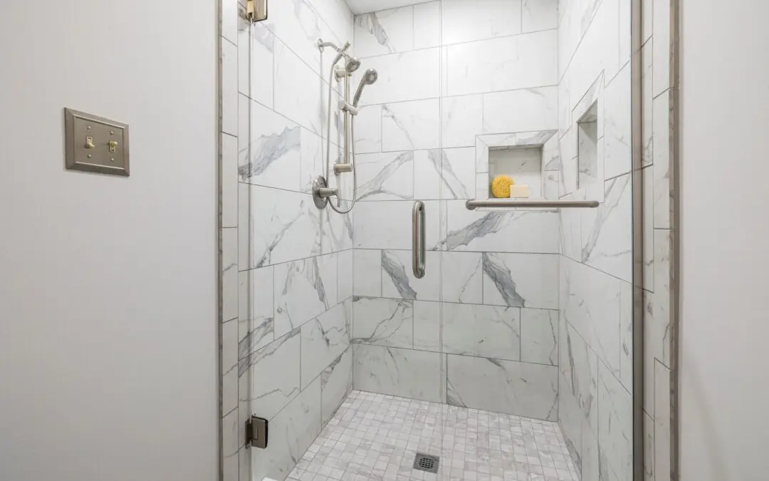 Elegant bathroom with white marble tiles and glass door, showcasing modern interior design.