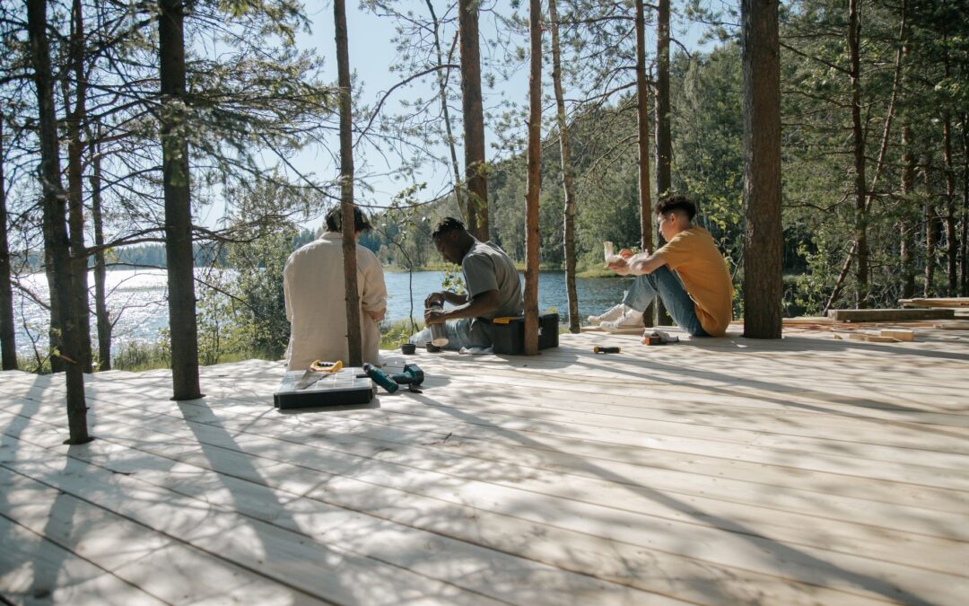 Group of workers enjoying a lunch break on a wooden deck in a serene forest setting.