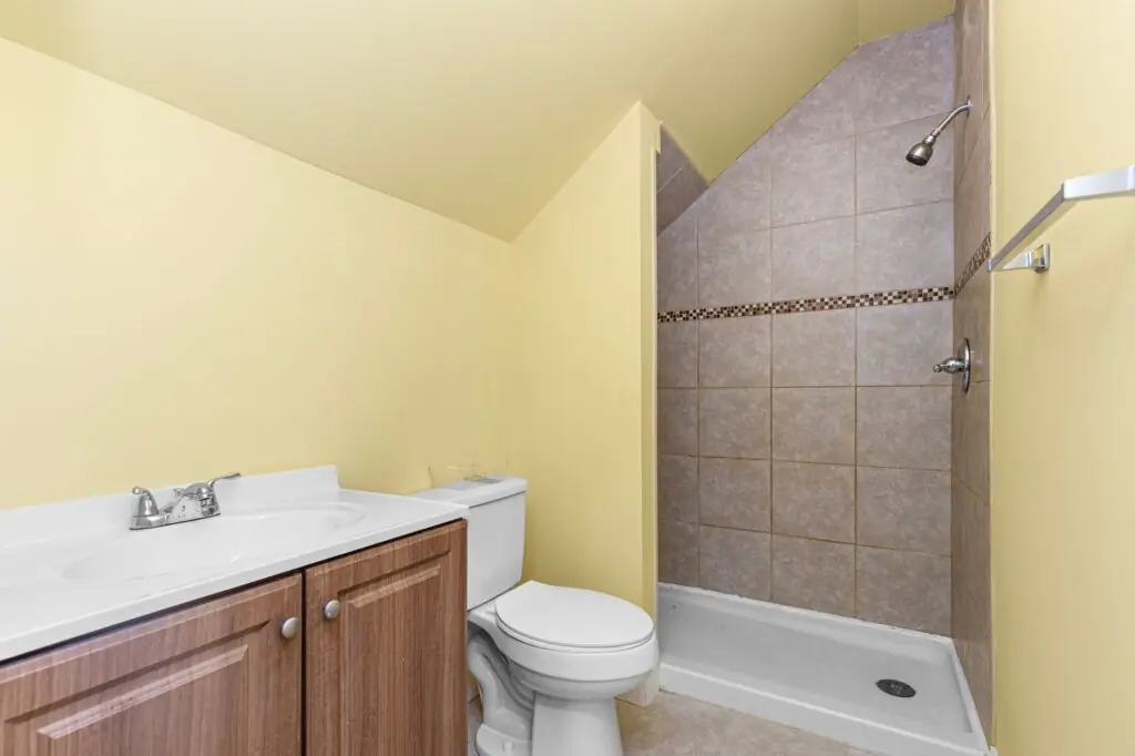 Modern yellow bathroom with shower, toilet, and wood vanity. Ideal for small spaces.