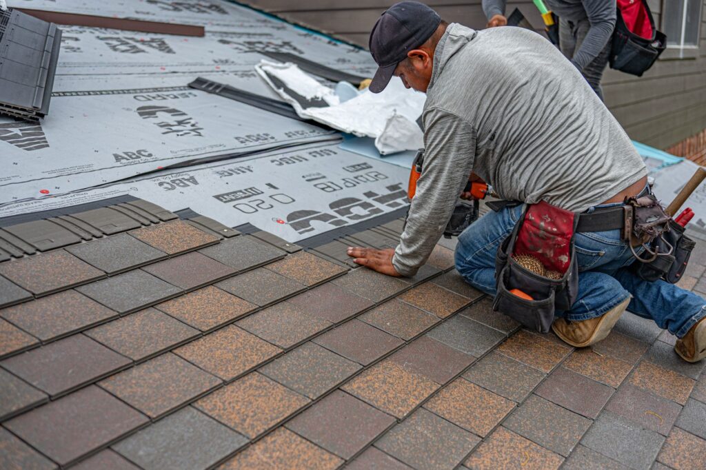 Skilled roofer installing asphalt shingles, ensuring quality home renovation.