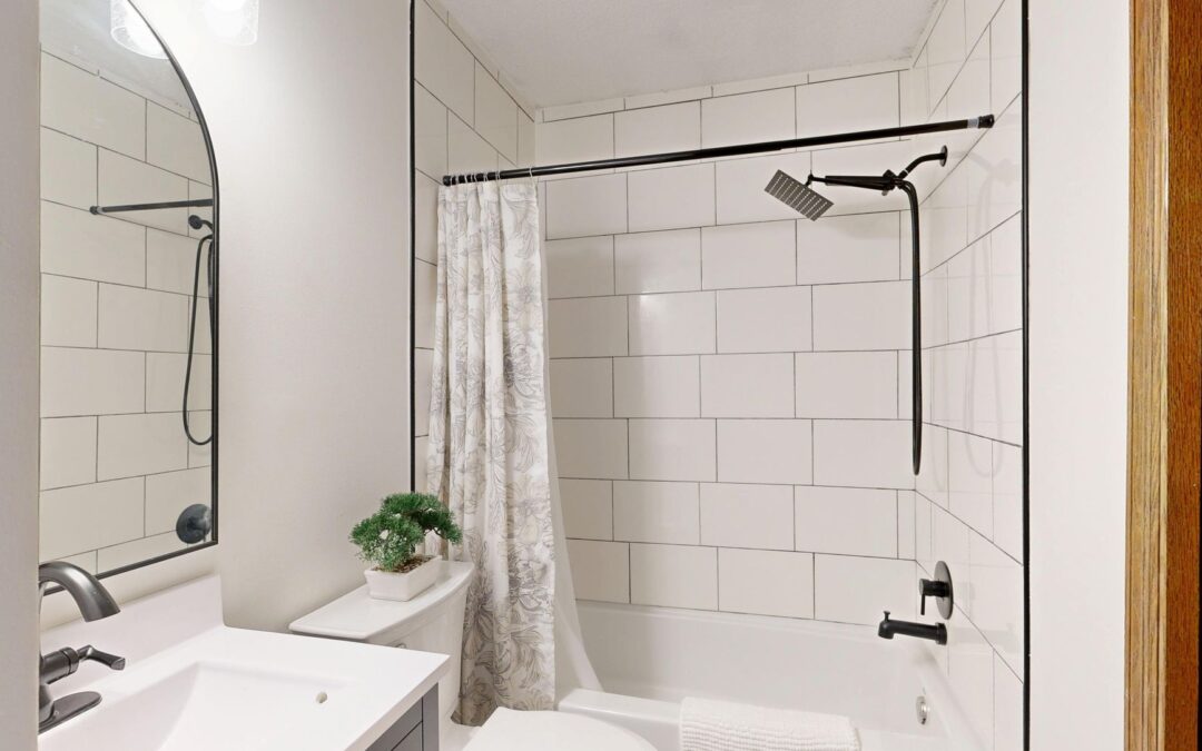 Sleek and clean modern bathroom with white tiles and black fixtures.