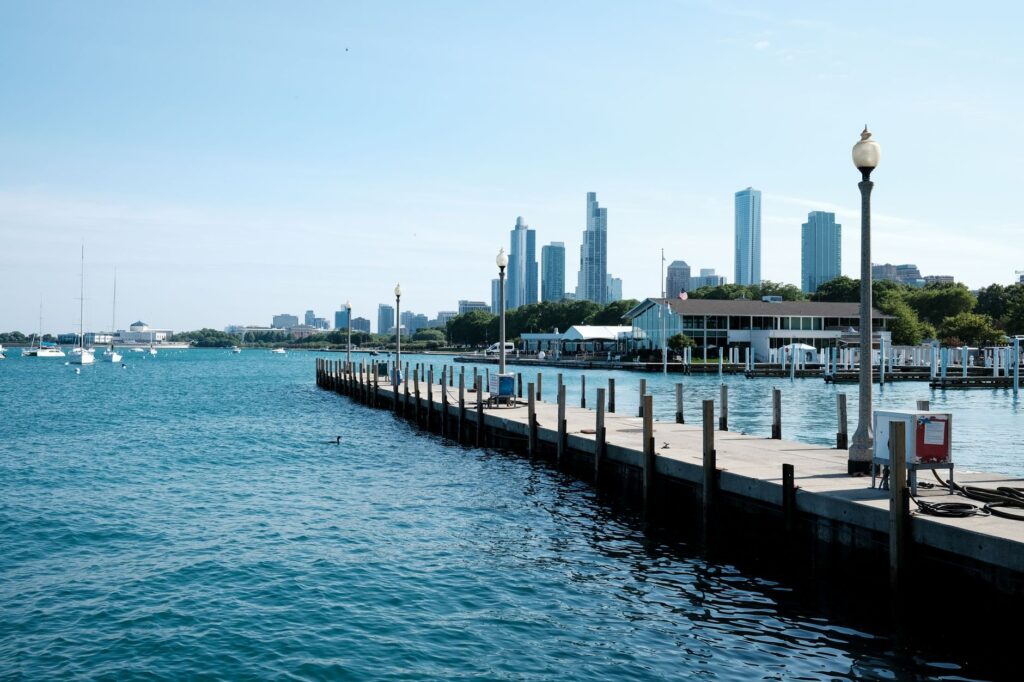 View of Chicago skyline with a lakeside pier, featuring blue skies and calm waters.