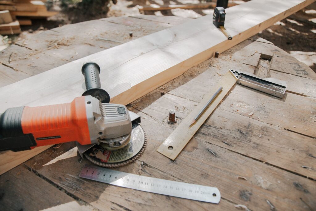 A close-up of carpentry tools including a grinder and ruler on a wooden workbench.