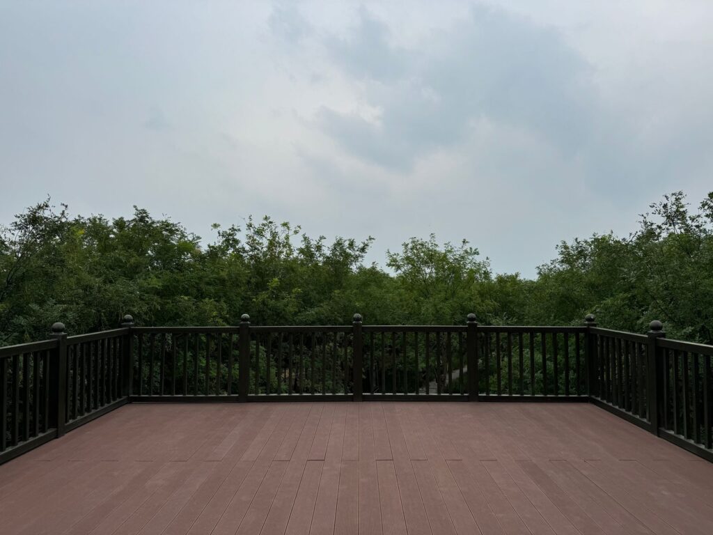 A peaceful wooden deck with a view of lush greenery under an overcast sky. Perfect for outdoor relaxation.