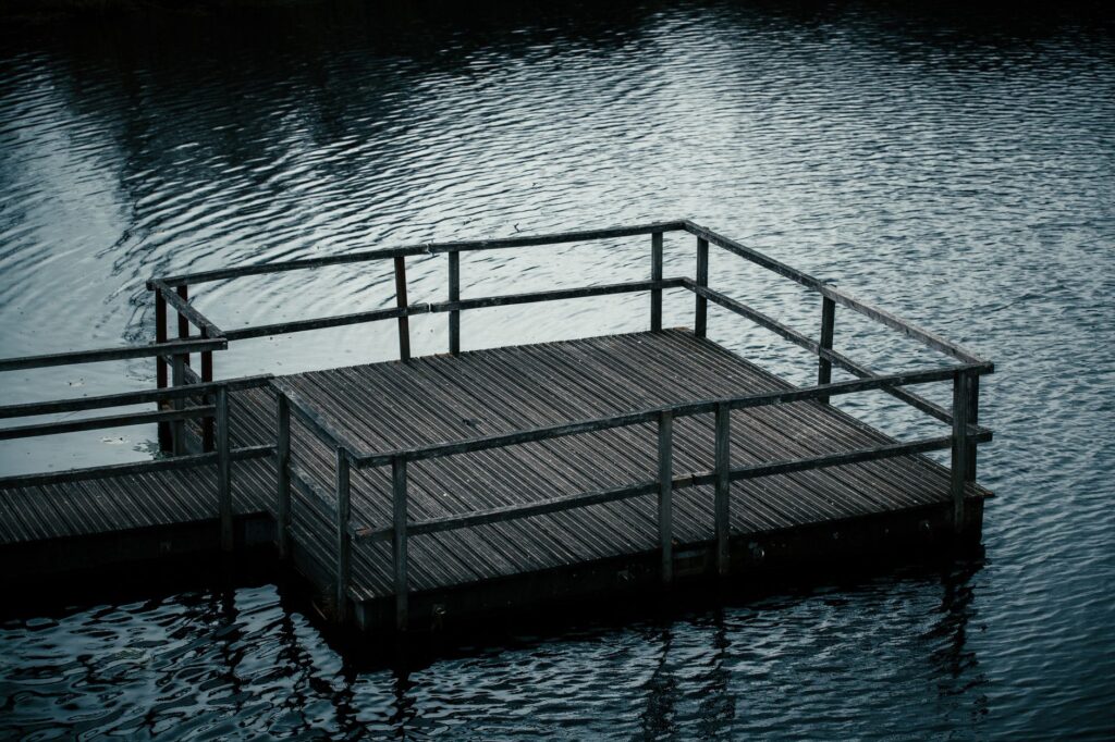 A serene image of a wooden deck on a calm water surface, ideal for relaxation themes.