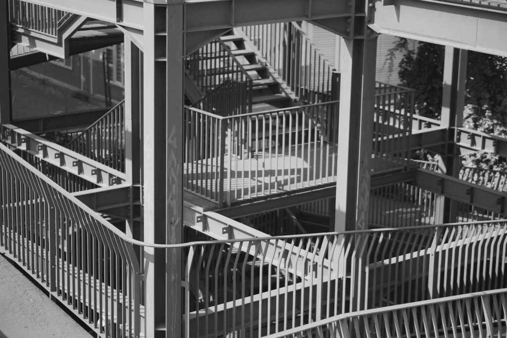 Black and white photo of a complex multi-level steel staircase outdoors.