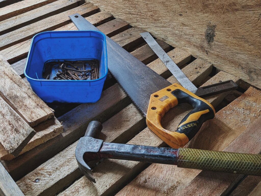 Close-up of carpentry tools including hammer, saw, and nails on a workplace.