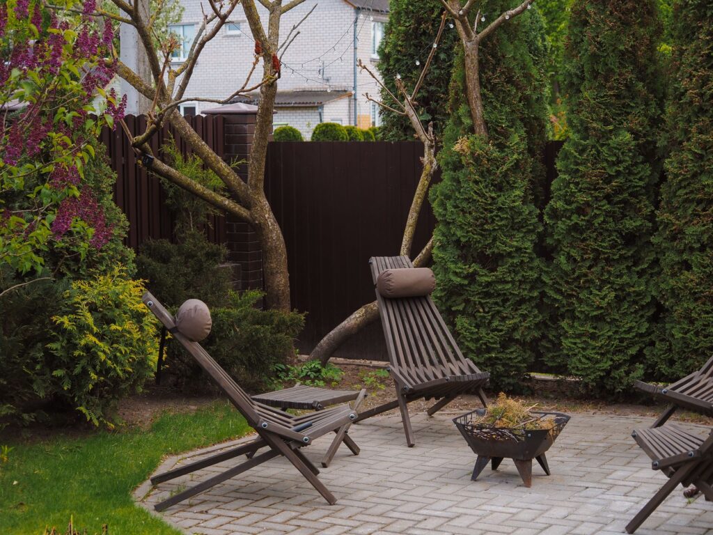 Cozy backyard featuring wooden lounge chairs and lush greenery, perfect for relaxation.