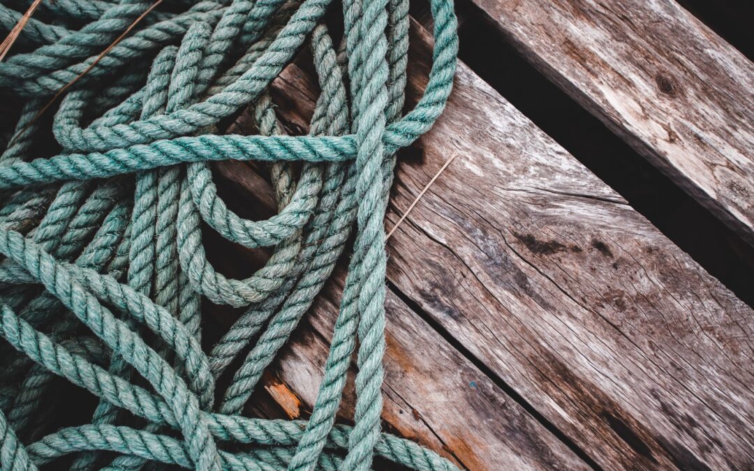 Detailed close-up of green rope on a weathered wooden surface, showcasing texture and color contrast.