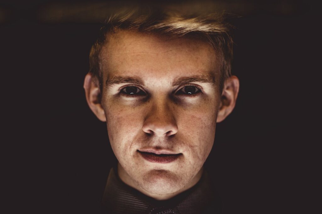 Dramatic close-up portrait highlighting the intense gaze of a young man.