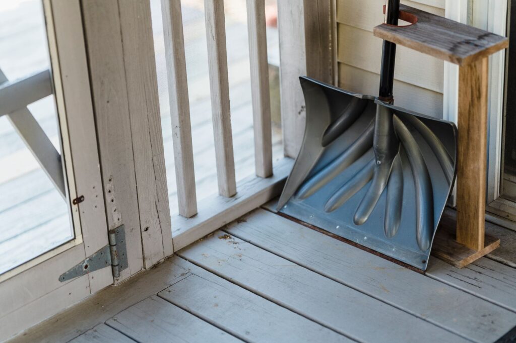 From above of wooden shovel with handle placed on floor of terrace near door