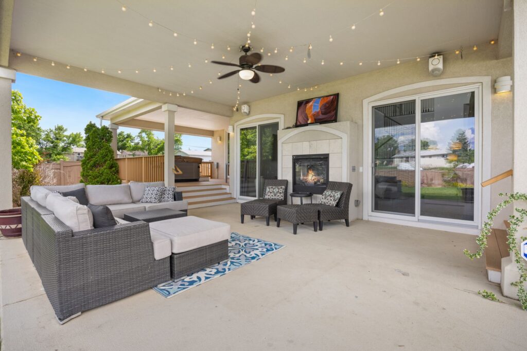 Luxurious outdoor patio featuring a cozy fireplace, modern furniture, and ambient string lights for a perfect relaxation s…
