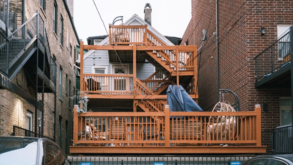 Multi-level wooden deck between urban buildings, showcasing unique architectural design.