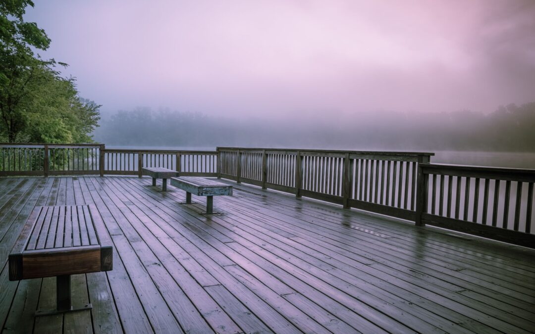 Serene view of a fog-covered lake from a wooden terrace at twilight, offering a peaceful getaway.
