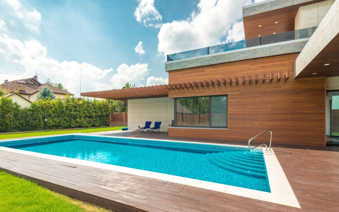 Spacious backyard with a modern house and swimming pool under a clear blue sky.