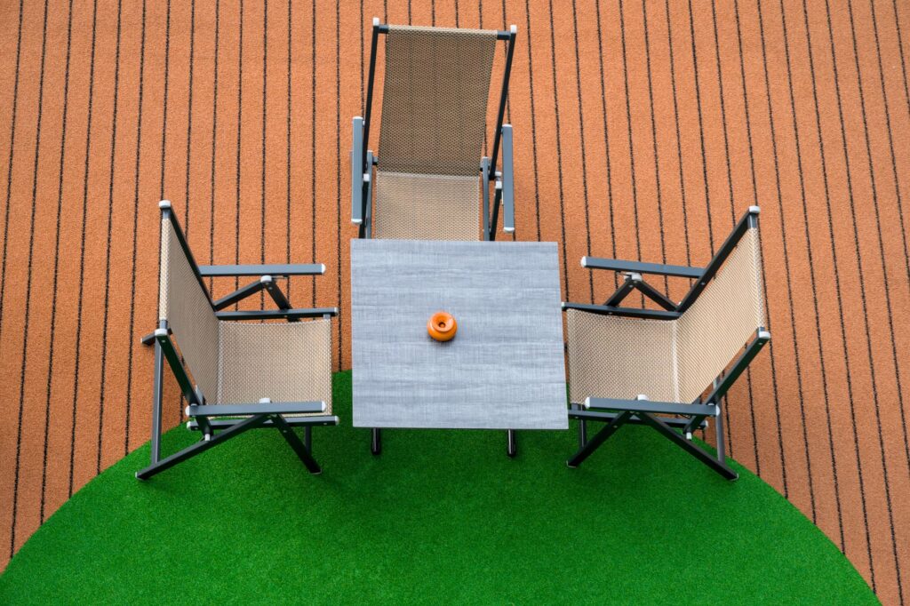 Top view of a modern patio furniture set with three chairs and a table on artificial grass.