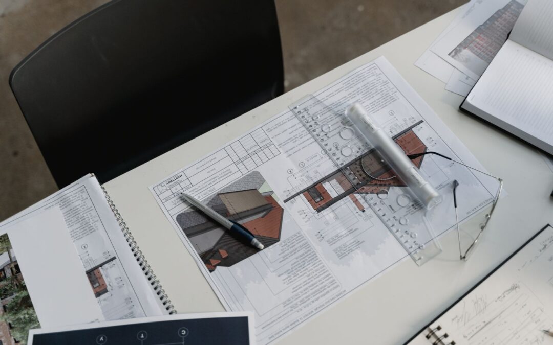Top view of architectural blueprints and drafting tools on a workspace desk.
