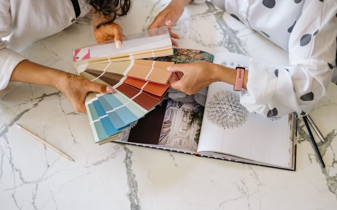 Two women in an office collaborating on color palettes for interior design planning.