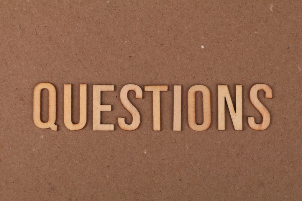 Wooden letters spelling the word "QUESTIONS" on a cardboard background, providing a neutral copyspace.
