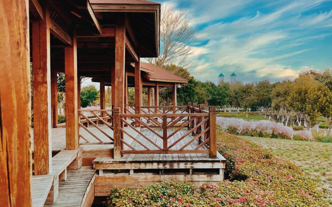 Wooden pavilion with rustic charm in a vibrant park, surrounded by lush greenery and colorful flowers.